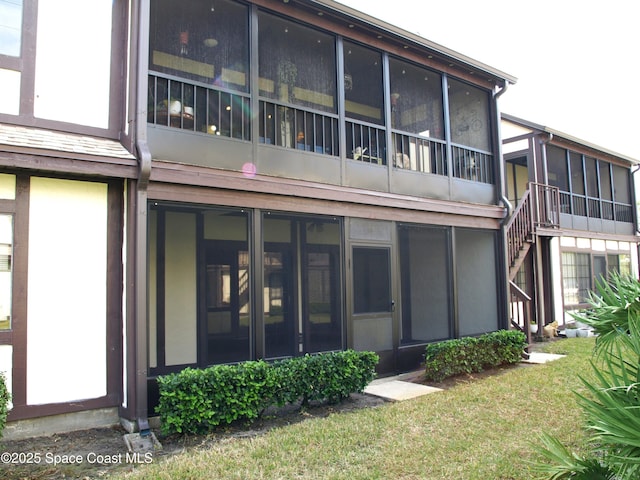 rear view of property featuring a lawn and a sunroom