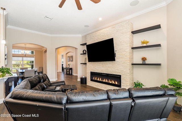 7690 Kerrington Dr, Melbourne, FL 32940 - living room with crown molding, dark wood-type flooring, a stone fireplace, and ceiling fan with notable chandelier