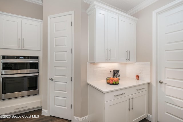 7690 Kerrington Dr, Melbourne, FL 32940 - kitchen featuring stainless steel double oven, crown molding, decorative backsplash, and white cabinets
