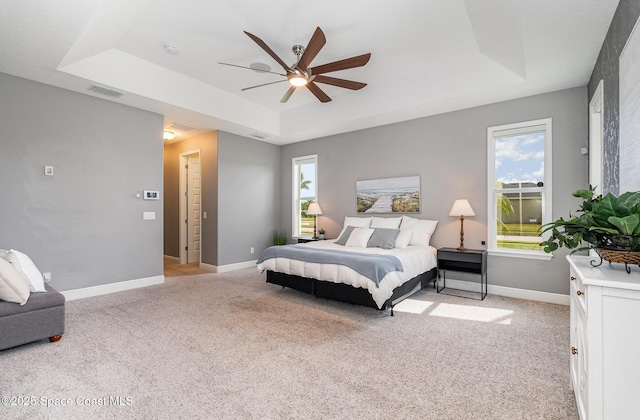 7690 Kerrington Dr, Melbourne, FL 32940 - carpeted bedroom featuring multiple windows, ceiling fan, and a tray ceiling