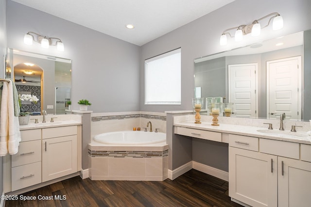 7690 Kerrington Dr, Melbourne, FL 32940 - bathroom featuring tiled tub, vanity, and wood-type flooring