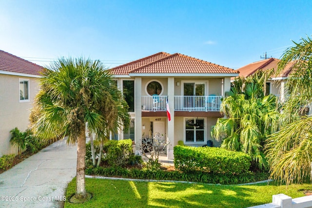 mediterranean / spanish-style house featuring a front yard and a balcony