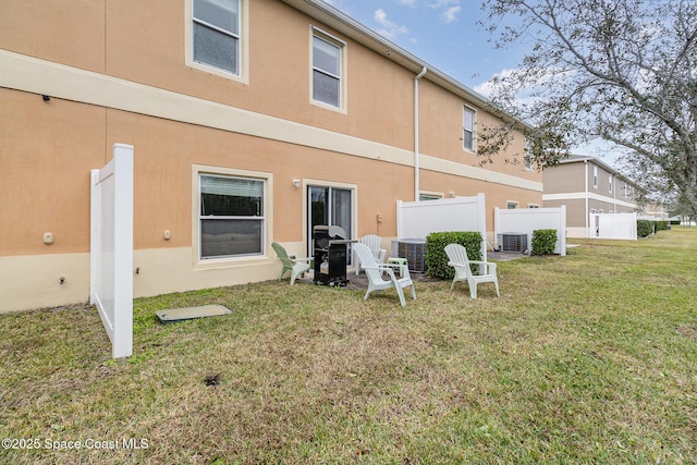 back of house featuring a lawn and central air condition unit