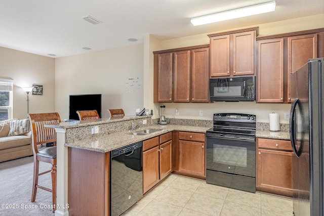 kitchen featuring black appliances, sink, kitchen peninsula, light tile patterned floors, and a breakfast bar area