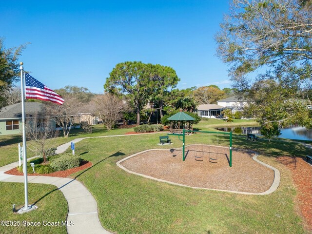 view of property's community with a lawn, a playground, and a water view