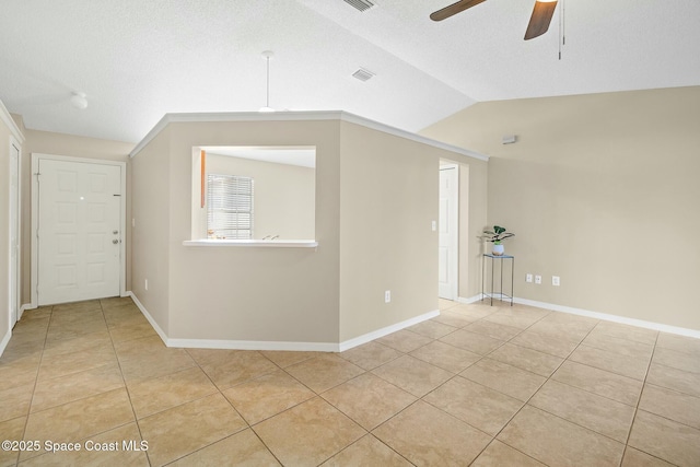 tiled empty room featuring vaulted ceiling, a textured ceiling, and ceiling fan