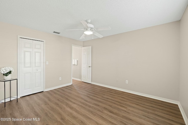 unfurnished bedroom with wood-type flooring, ceiling fan, a textured ceiling, and a closet