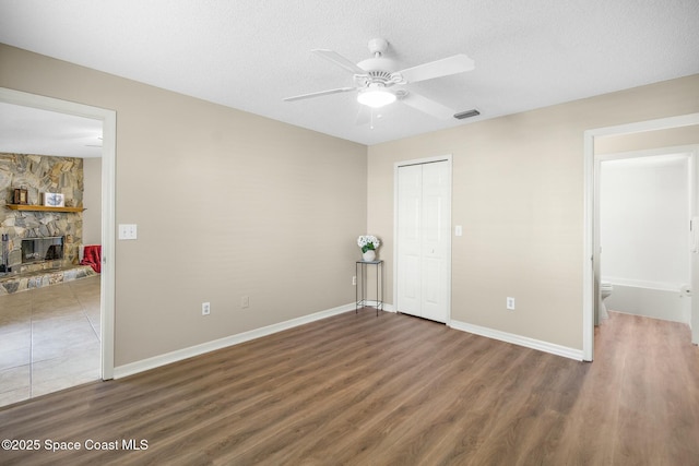 unfurnished bedroom featuring dark wood-type flooring, a closet, a fireplace, and a textured ceiling