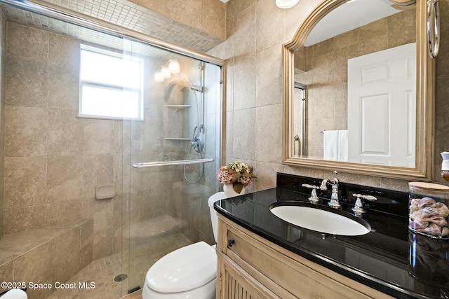 bathroom with tile walls, vanity, toilet, and walk in shower