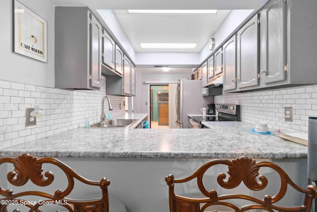 kitchen featuring decorative backsplash, sink, kitchen peninsula, and stainless steel appliances