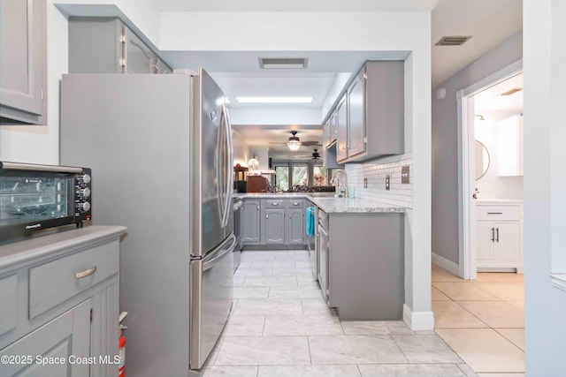 kitchen with decorative backsplash, sink, ceiling fan, light tile patterned floors, and gray cabinetry