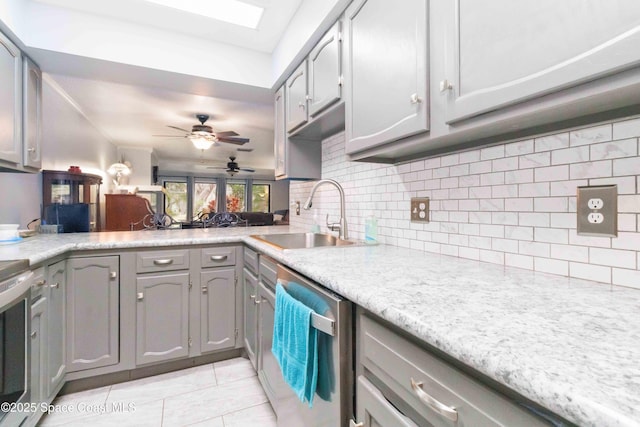 kitchen featuring light tile patterned floors, gray cabinetry, decorative backsplash, dishwasher, and sink