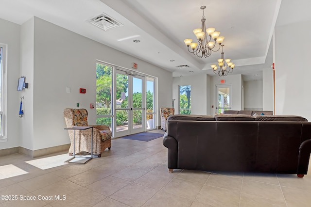 tiled living room with french doors, an inviting chandelier, and a raised ceiling