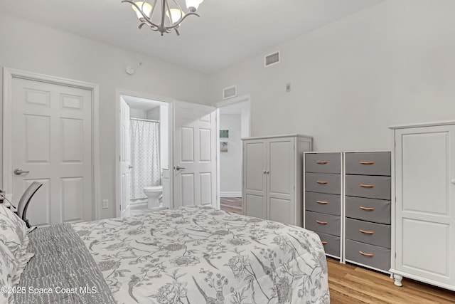 bedroom featuring ensuite bath, an inviting chandelier, and light hardwood / wood-style floors