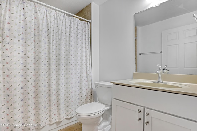 bathroom with toilet, vanity, and tile patterned flooring