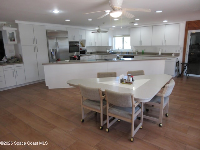 kitchen with a kitchen island, a breakfast bar, sink, appliances with stainless steel finishes, and white cabinets