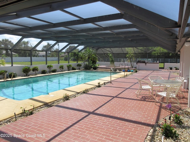 view of swimming pool with glass enclosure and a patio