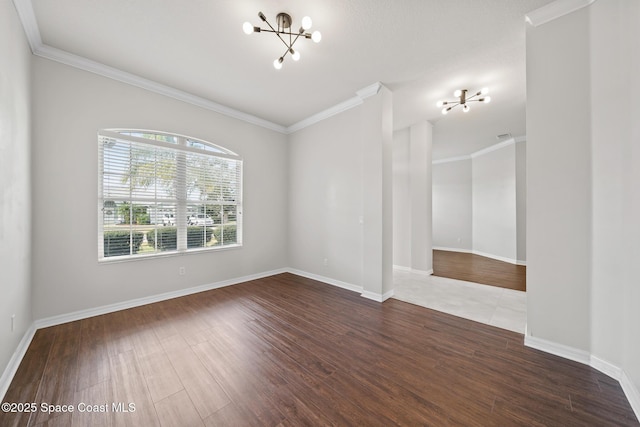 empty room featuring wood-type flooring, ornamental molding, and an inviting chandelier