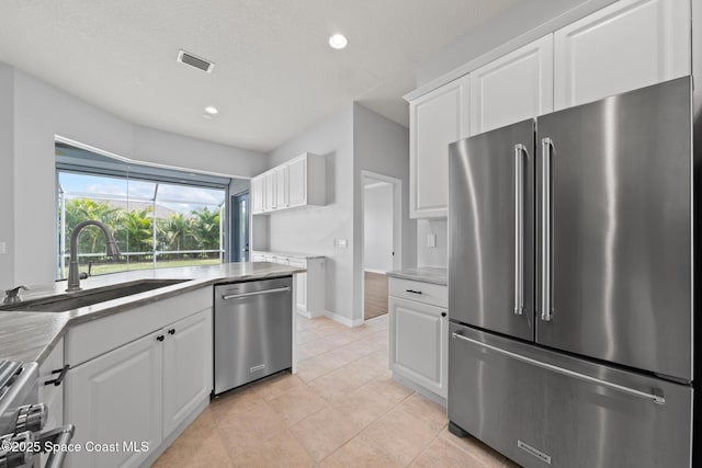 kitchen featuring appliances with stainless steel finishes, sink, white cabinetry, and light tile patterned flooring