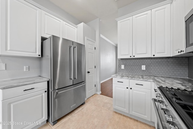 kitchen featuring light tile patterned floors, appliances with stainless steel finishes, decorative backsplash, white cabinets, and light stone counters