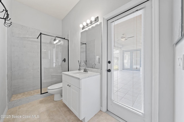 bathroom with tile patterned floors, tiled shower, vanity, and toilet