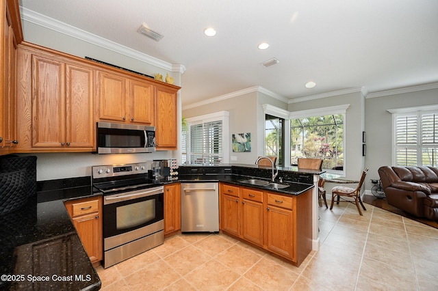 kitchen with sink, ornamental molding, stainless steel appliances, and dark stone counters