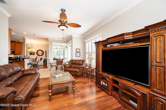 living room featuring ceiling fan with notable chandelier, hardwood / wood-style flooring, and ornamental molding