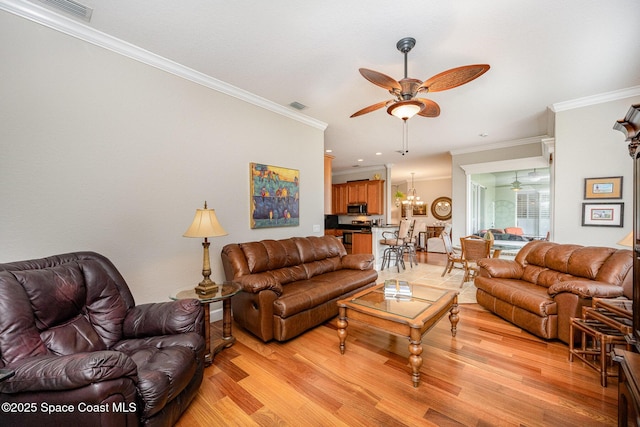 living room with ceiling fan with notable chandelier, light hardwood / wood-style flooring, and ornamental molding