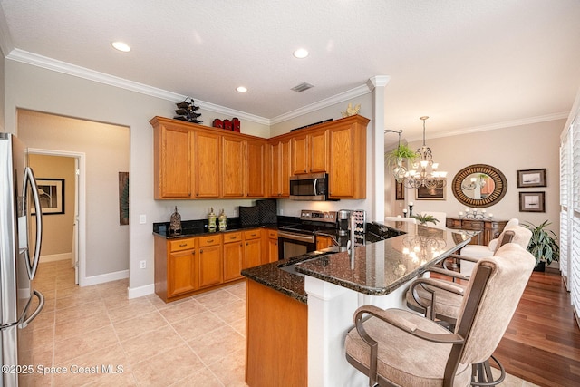 kitchen with decorative light fixtures, stainless steel appliances, a kitchen breakfast bar, kitchen peninsula, and ornamental molding