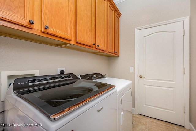 laundry room featuring light tile patterned flooring, washer and dryer, and cabinets