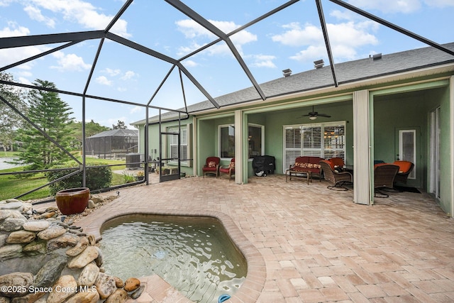 rear view of house featuring glass enclosure, ceiling fan, a patio area, and an outdoor living space