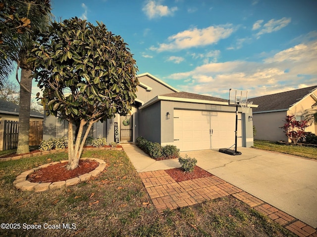 view of front of house featuring an attached garage, concrete driveway, fence, and stucco siding