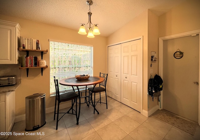 tiled dining area featuring an inviting chandelier, lofted ceiling, and a textured ceiling