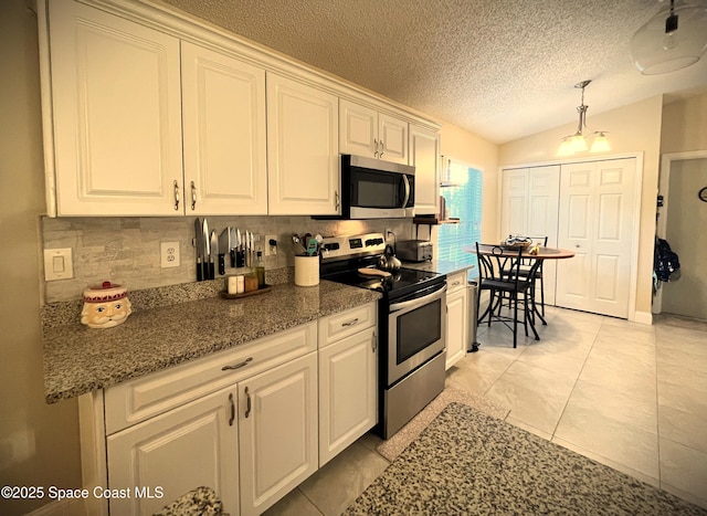 kitchen featuring lofted ceiling, light tile patterned floors, pendant lighting, stainless steel appliances, and white cabinets