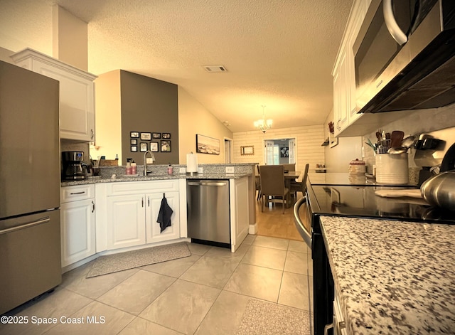 kitchen with light tile patterned flooring, white cabinetry, vaulted ceiling, appliances with stainless steel finishes, and light stone countertops