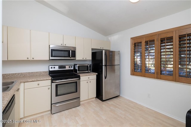 kitchen featuring lofted ceiling, appliances with stainless steel finishes, sink, and light hardwood / wood-style floors