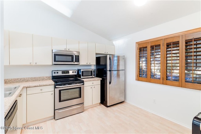 kitchen with light hardwood / wood-style floors, sink, appliances with stainless steel finishes, high vaulted ceiling, and white cabinets