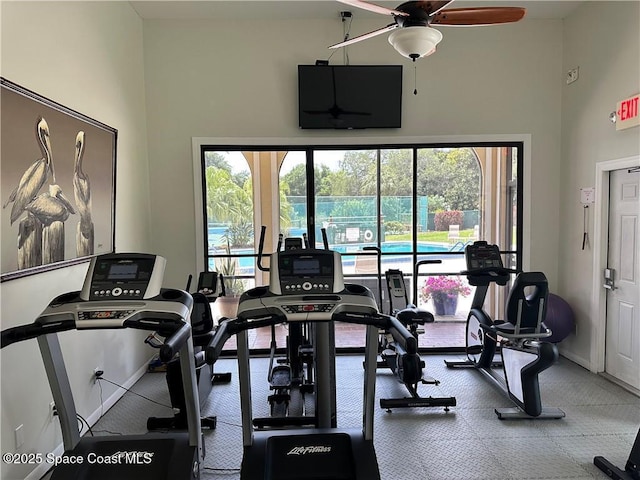 exercise room featuring ceiling fan, plenty of natural light, and a towering ceiling