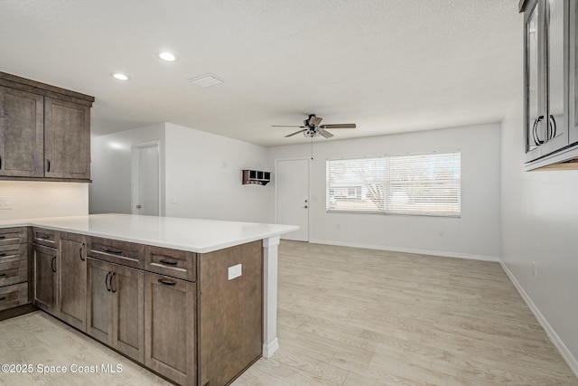 kitchen with ceiling fan, dark brown cabinetry, kitchen peninsula, and light hardwood / wood-style floors