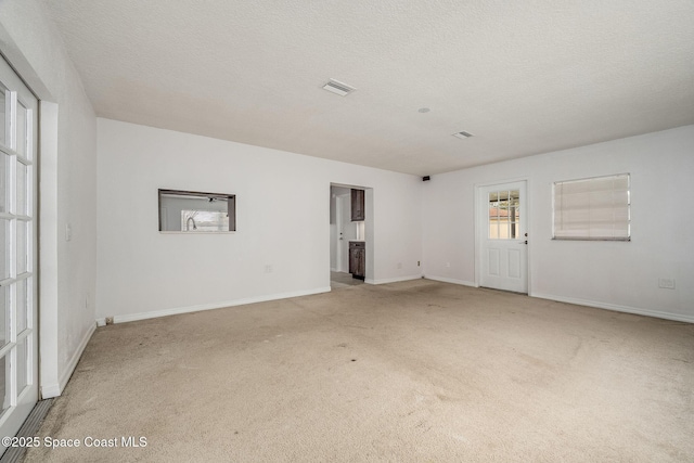 carpeted empty room featuring a textured ceiling