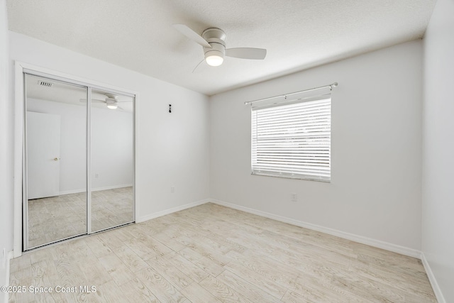 unfurnished bedroom with ceiling fan, a closet, light hardwood / wood-style flooring, and a textured ceiling