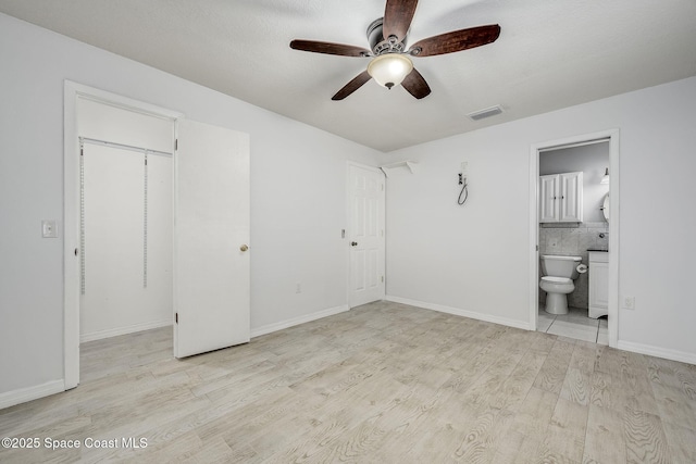 unfurnished bedroom with ceiling fan, ensuite bath, and light hardwood / wood-style flooring