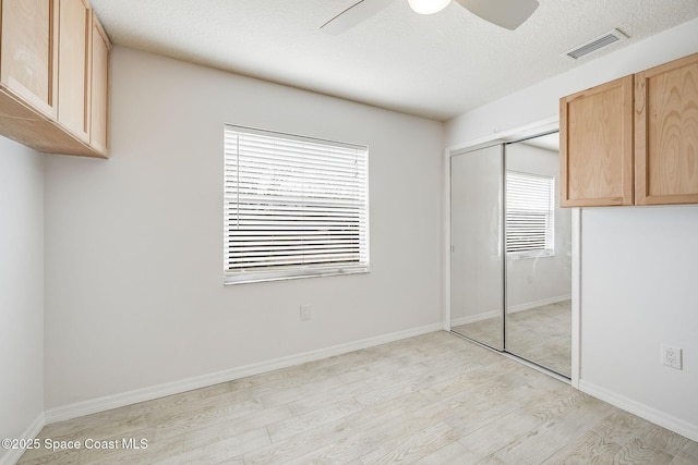 unfurnished bedroom with ceiling fan, light hardwood / wood-style flooring, a closet, and a textured ceiling