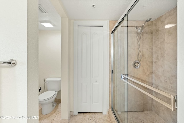 bathroom with toilet, a textured ceiling, and an enclosed shower