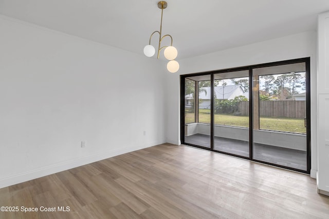 spare room featuring light hardwood / wood-style floors and an inviting chandelier