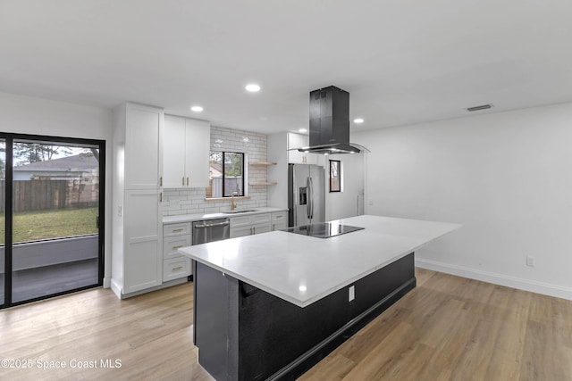 kitchen with a center island, white cabinetry, stainless steel appliances, light hardwood / wood-style floors, and island range hood