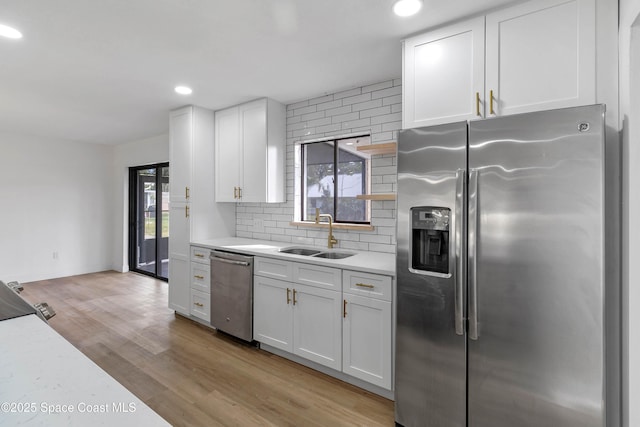 kitchen featuring backsplash, appliances with stainless steel finishes, sink, and white cabinetry