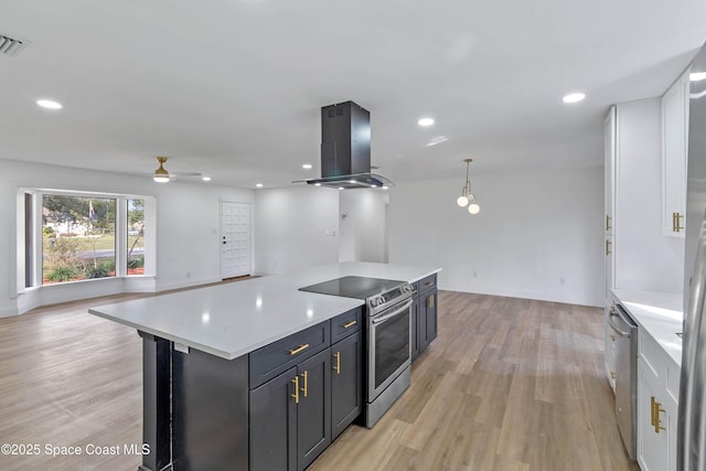 kitchen featuring island range hood, appliances with stainless steel finishes, hanging light fixtures, a kitchen island, and light hardwood / wood-style flooring