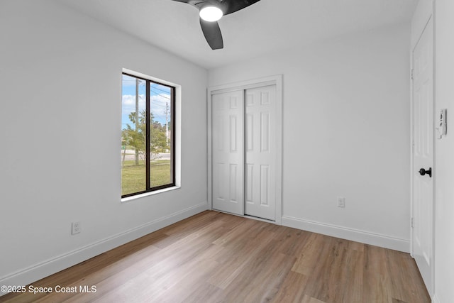 unfurnished bedroom with a closet, ceiling fan, light hardwood / wood-style floors, and multiple windows