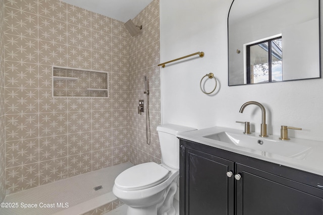 bathroom with toilet, vanity, and a tile shower